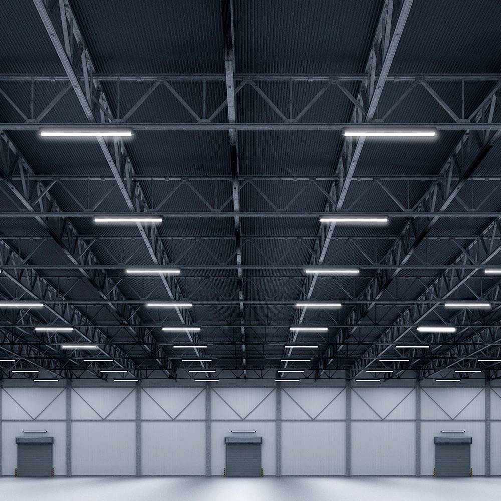 A large warehouse with high ceilings, industrial lighting and several closed roller shutters on the ground floor, which appears tidy and empty.