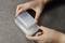 Two hands are stacking transparent rectangular plastic containers on a grey surface.