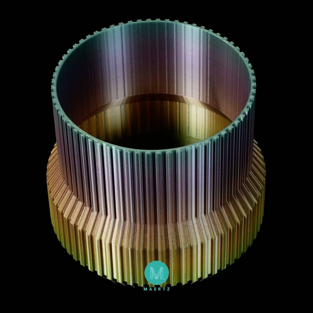 A cylindrical object with colourful, vertical ribs creating a shimmering effect. At the bottom is a small blue logo.