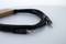 A black audio cable with 3.5mm jack connectors at both ends is lying on a white surface.