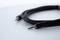 A black audio cable with two 3.5mm plugs lies on a white surface.