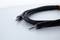 A black audio cable with two 3.5 mm jack plugs lies on a white background.