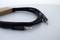 A black audio cable with two 3.5 mm jack plugs lies on a white surface.