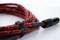 A red, patterned cable with a black plug is lying on a white surface. It is fastened together with a hook and loop fastener.