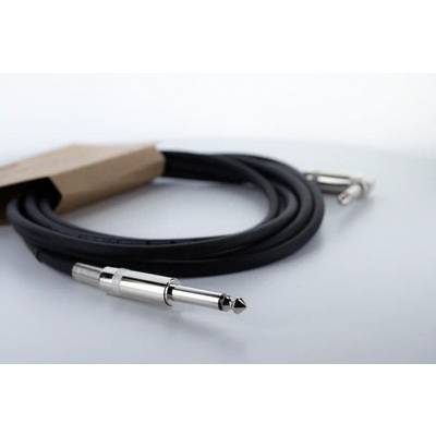 A black audio cable with metal plugs lies on a white surface.
