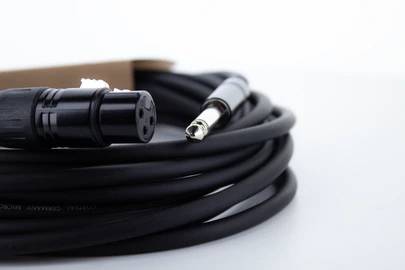 An coiled audio cable with XLR and jack plugs lies on a white surface.