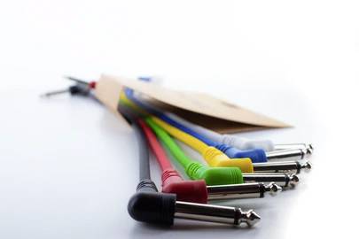 Several colourful audio cables with different plugs are lying on a table. They are black, red, green, yellow, blue and white.