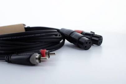Cable with XLR and RCA connectors, coiled on a surface, symbolise audio connections or audio technology.