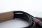 A bundle of black cables with plugs, partially protruding from a brown cardboard box, against a light background.