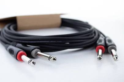 A black and red audio cable with multiple jack plugs lies on a white background. Ideal for musical instruments.