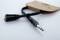 'Audio jack cable with Y-splitter, a black cable and silver plug, on white background. Packaging in the background.'