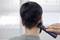 A person is shown from behind while their hair is being trimmed with an electric razor. Focus is on the nape of the neck.