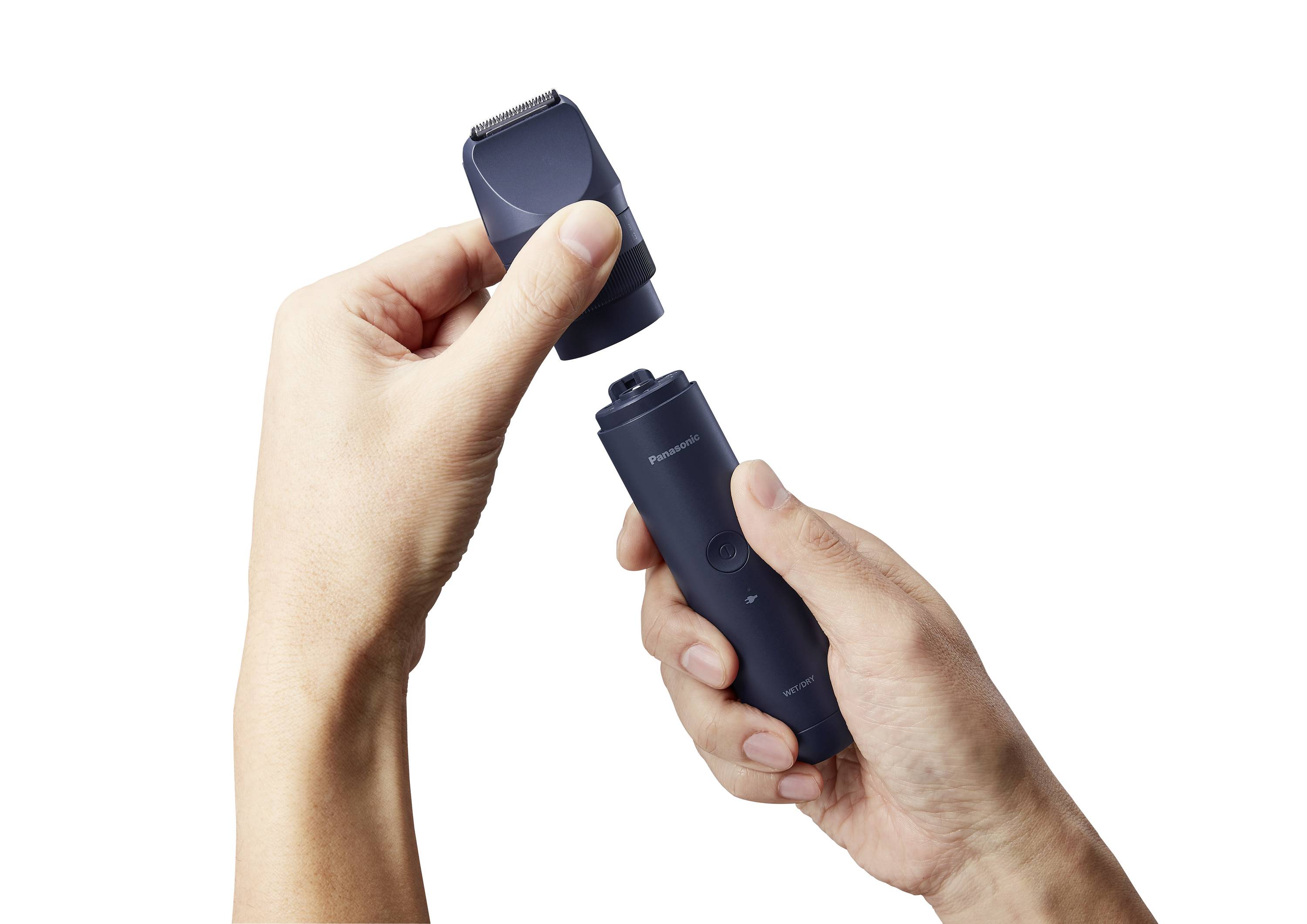 Two hands are holding an electric razor; one hand is removing the razor head from the handle.