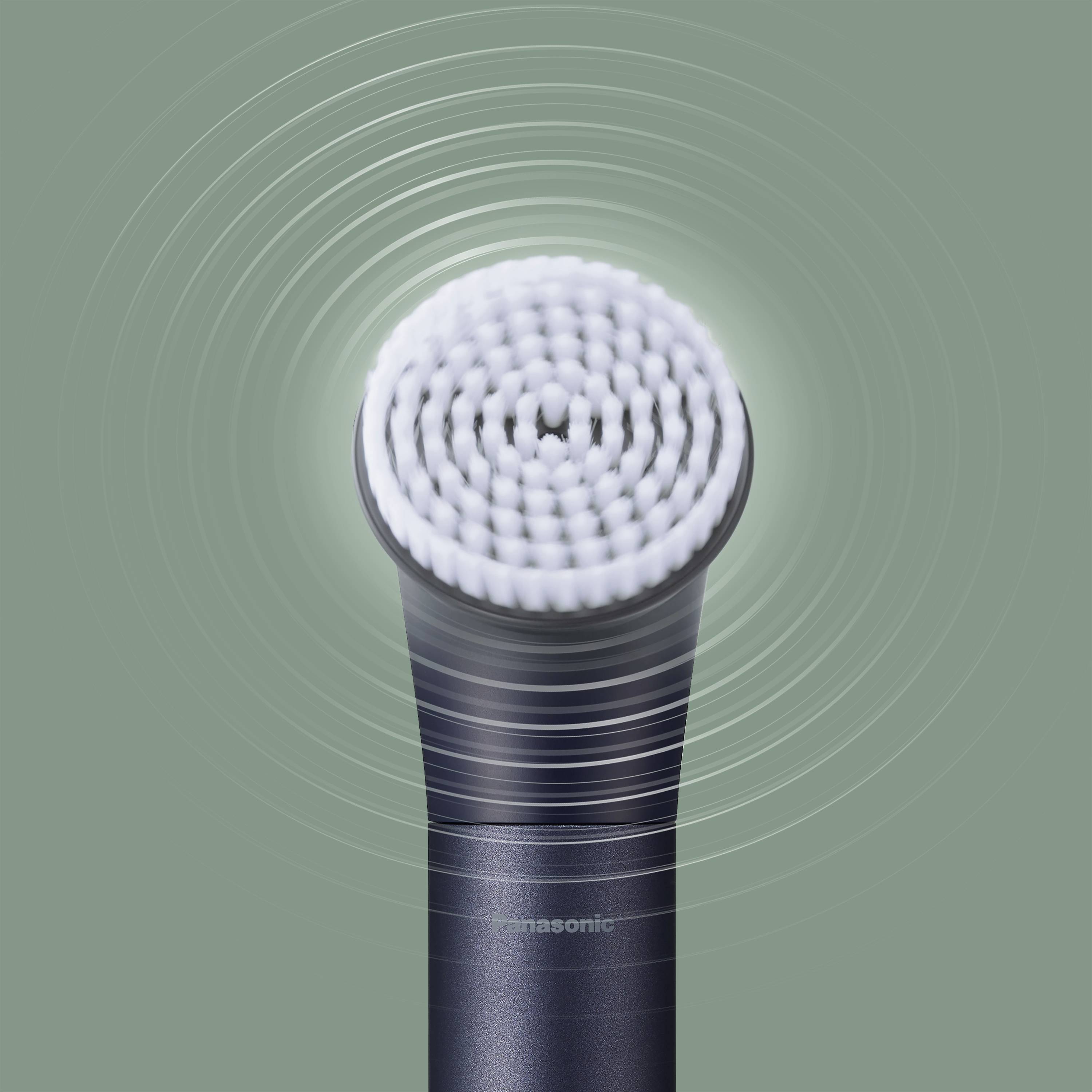 Electric toothbrush with a circular brush head displaying vibrations, against a green background.