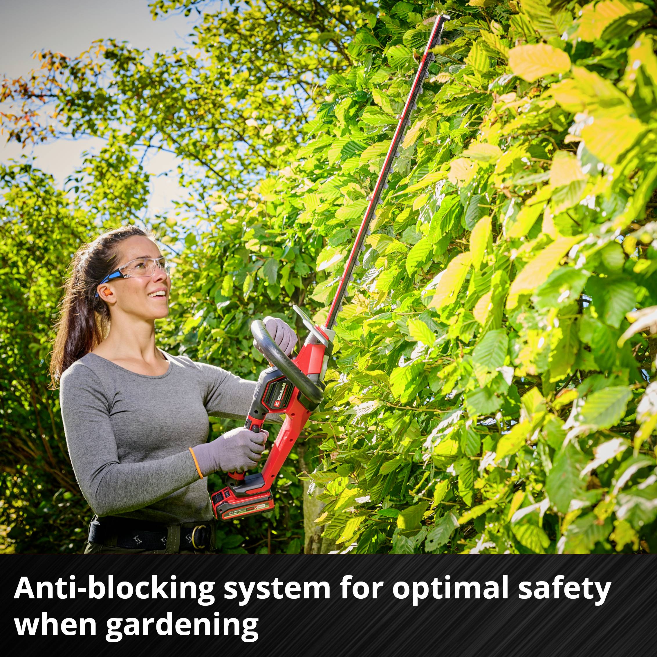A person is trimming a green hedge with hedge shears. Text at the bottom of the image reads: 'Anti-lock system for optimal safety during garden work'.