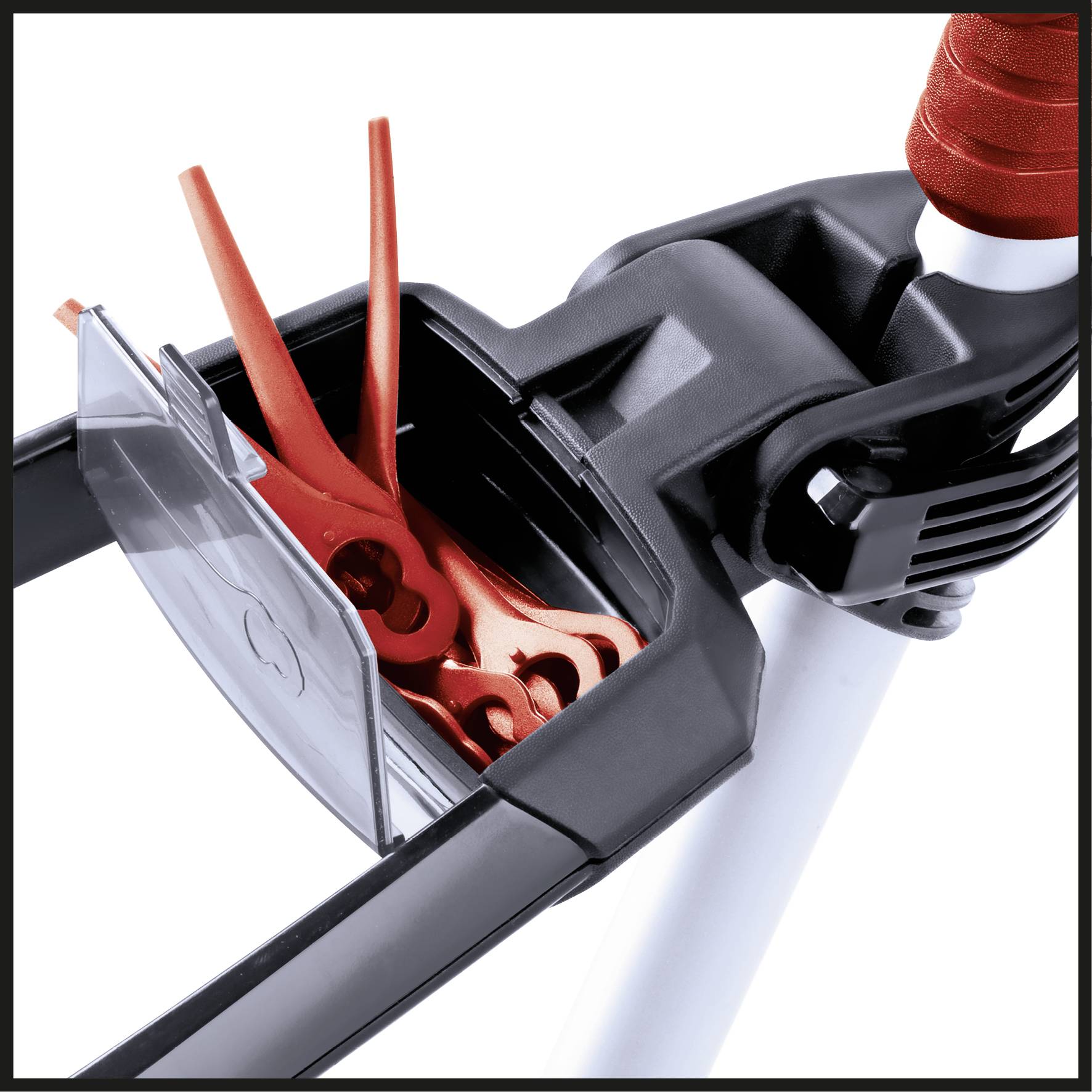 A close-up of a lawnmower component with an opening housing red plastic blades.