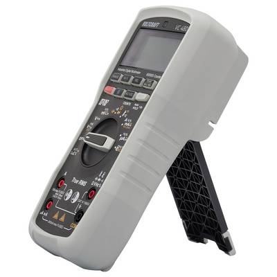 Digital multimeter with display and rotary switch, resting on a black stand. Used for measuring electrical units.