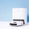 A white robot vacuum cleaner docking at its charging station against a light blue background.