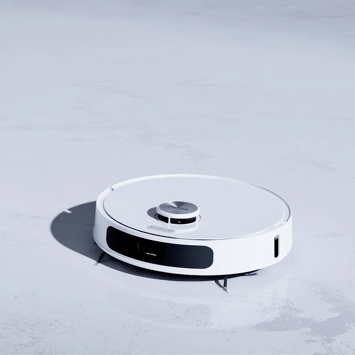 A white robotic vacuum cleaner is moving across a smooth floor.