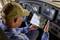 A man in the cab of a lorry looks at a tablet with a navigation map and route information.