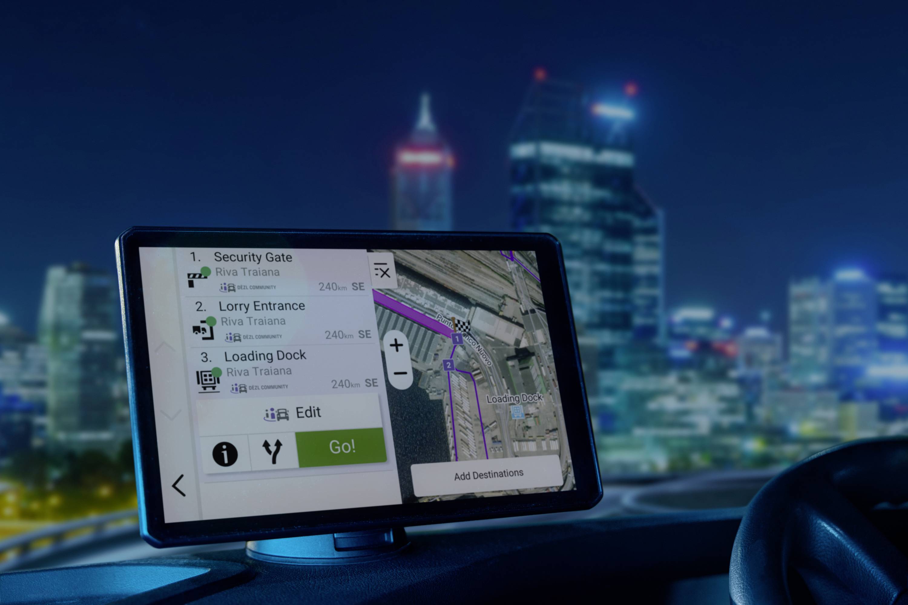 A satellite navigation system in the car displays instructions for 'Safety Check', 'Lorry Entrance' and 'Loading Area'. Background: City at night.
