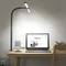 A laptop on a desk displays an open webpage. Beside it are a mug, books, and a desk lamp shining brightly.