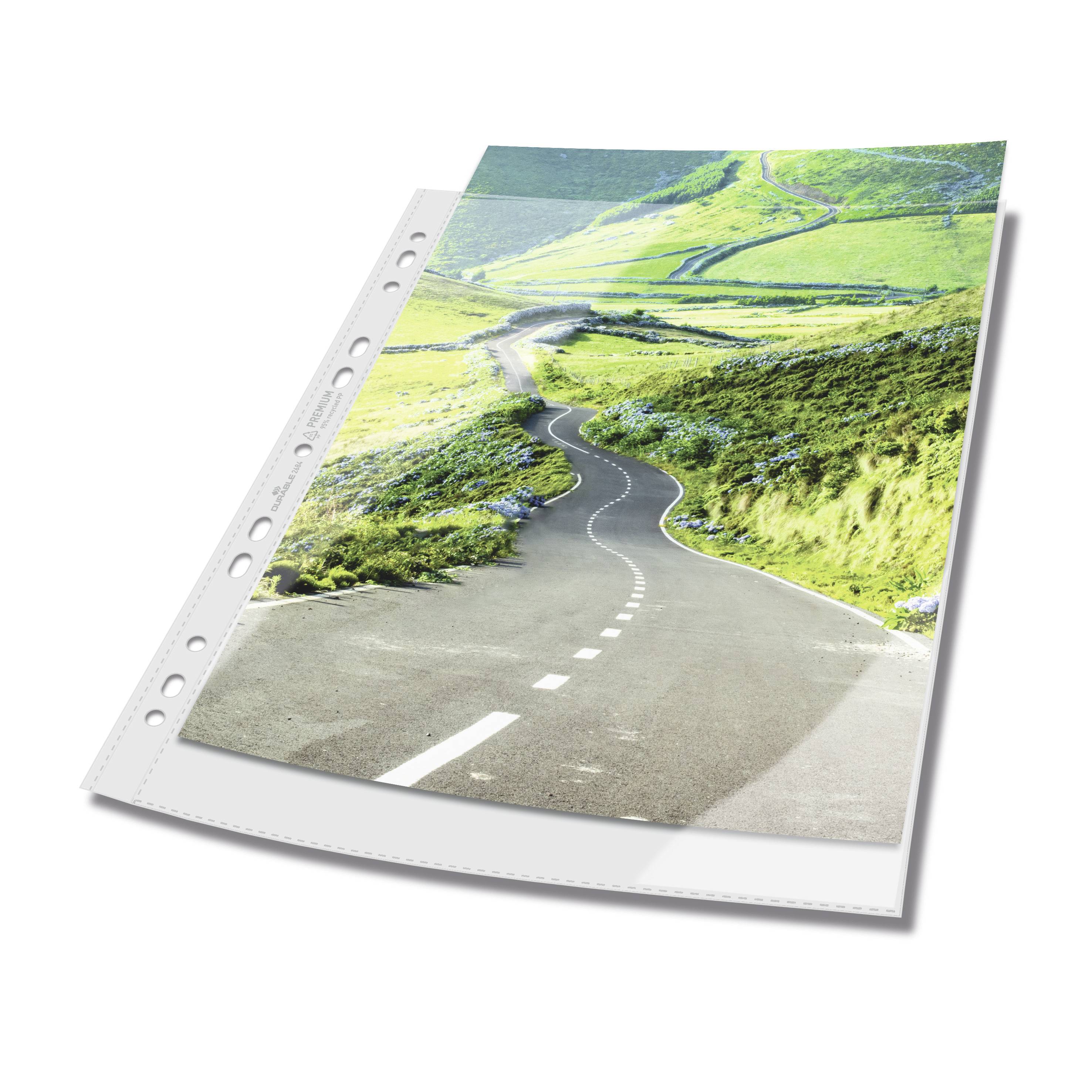 An empty plastic sleeve contains a photograph of a winding road traversing a verdant, hilly landscape.