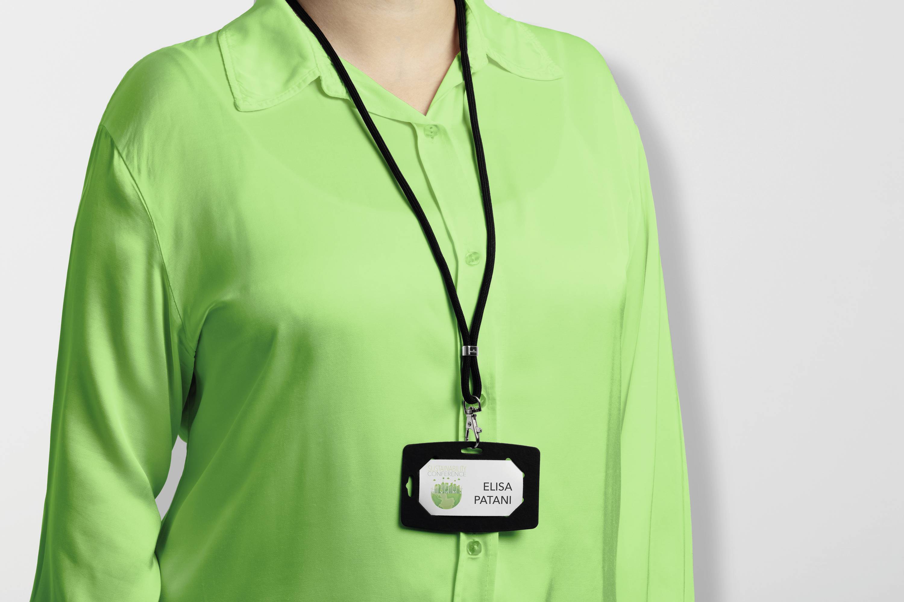 A person is wearing a green shirt and a black lanyard with an ID badge that reads 'Elisa Patan'.