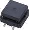 A black electronic component with a square shape and two metal connections at the bottom, positioned on a light surface.