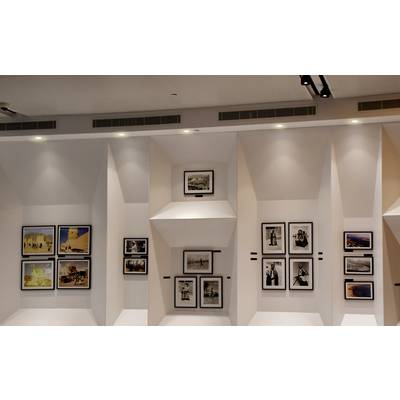 Art gallery wall displaying framed photographs of various sizes in a modern, well-lit setting.