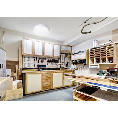 A well-organized workshop featuring tools hanging on a pegboard, wooden workbenches, and shelves with woodworking supplies.