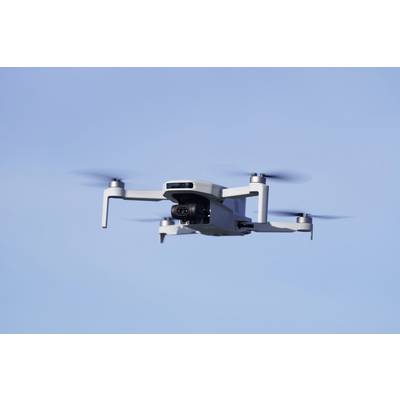 A white drone flies in the clear blue sky, its rotor blades spinning rapidly.