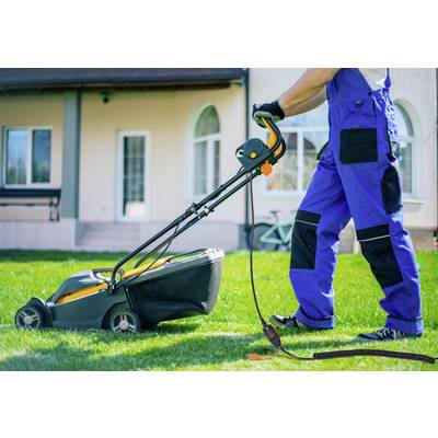 A person is mowing the lawn with an electric lawnmower, wearing blue workwear. A house is visible in the background.