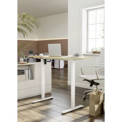 A height-adjustable desk with a laptop and notebook in a modern office, next to a white office chair and a plant.