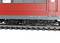 A red train on railway tracks, close-up of the undercarriage. Suspension and wheel details are visible. No people or landscape present.
