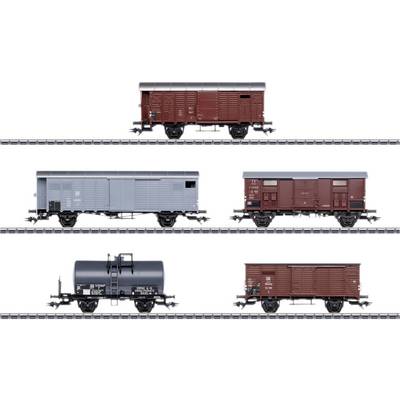 Three different freight train wagons on railway tracks: A brown one at the top, a grey one in the middle, and a black tanker wagon at the bottom.