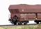 A brown Deutsche Bahn freight wagon is travelling on a railway track, loaded with black coal.