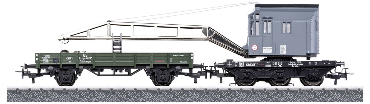 Two model railway wagons: On the left, a green goods wagon, on the right, a grey crane wagon with an extended crane arm.
