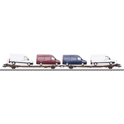 Four delivery vans in white, red, blue, and white are loaded onto a railway wagon. They are parked side by side in a row.