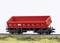 A red railway goods wagon on tracks in a model landscape. The wagon is intricately designed and realistically presented.