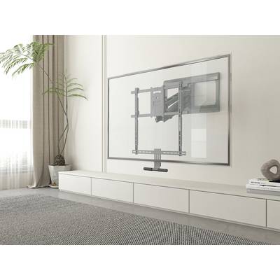 A modern living room with a flat television mounted on the wall, a large pot with a plant standing to the left of it.