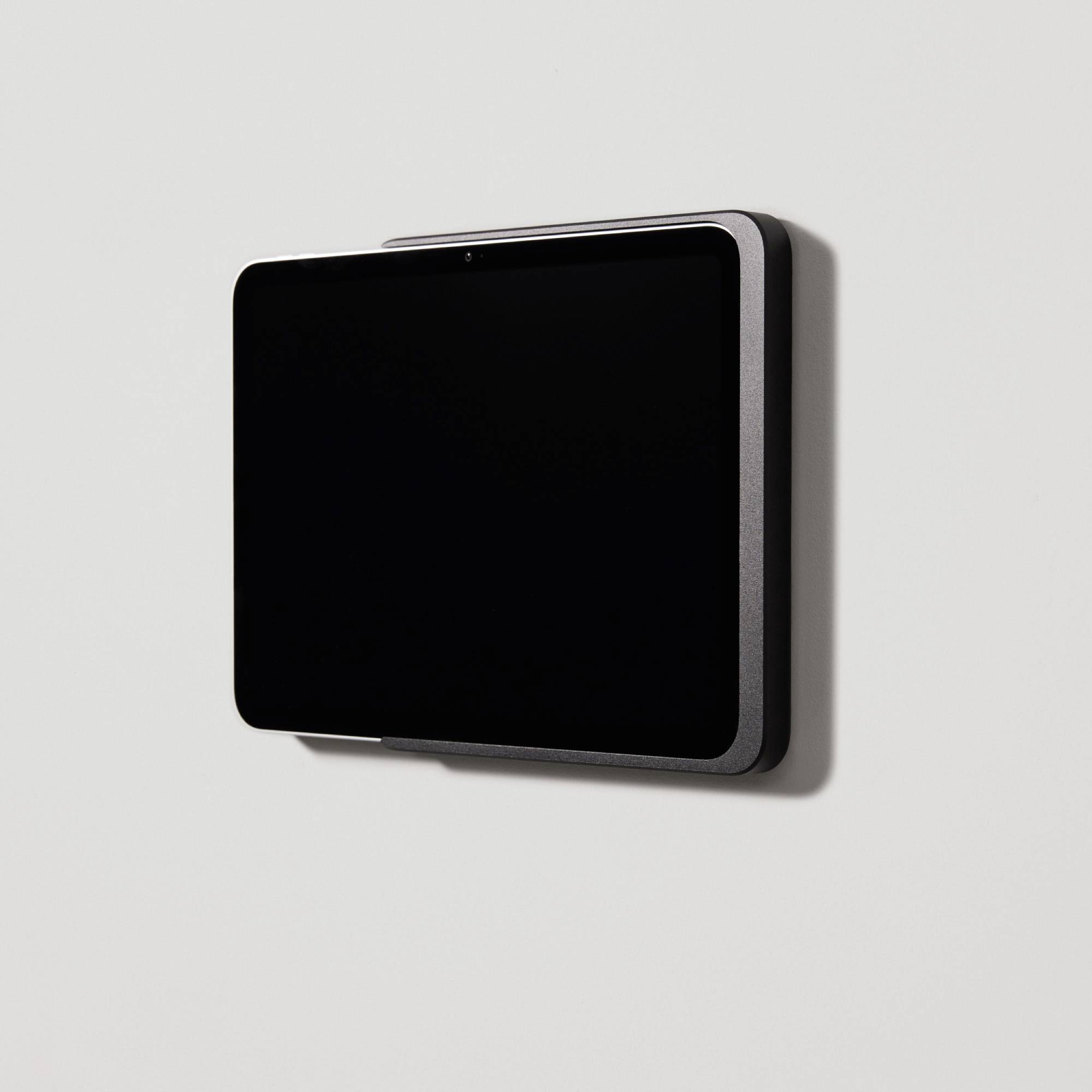 A black screen with a slim border is hanging on a white wall.