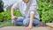 A person in casual clothing is screwing a screw into a wooden board outdoors in a garden using a screwdriver.