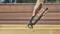 A hand is holding a green pair of pliers to pull a nail from a wooden board. Background of wooden planks.