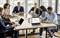 A group of people in a modern office during a meeting. They are working on laptops, discussing documents and analysing diagrams.