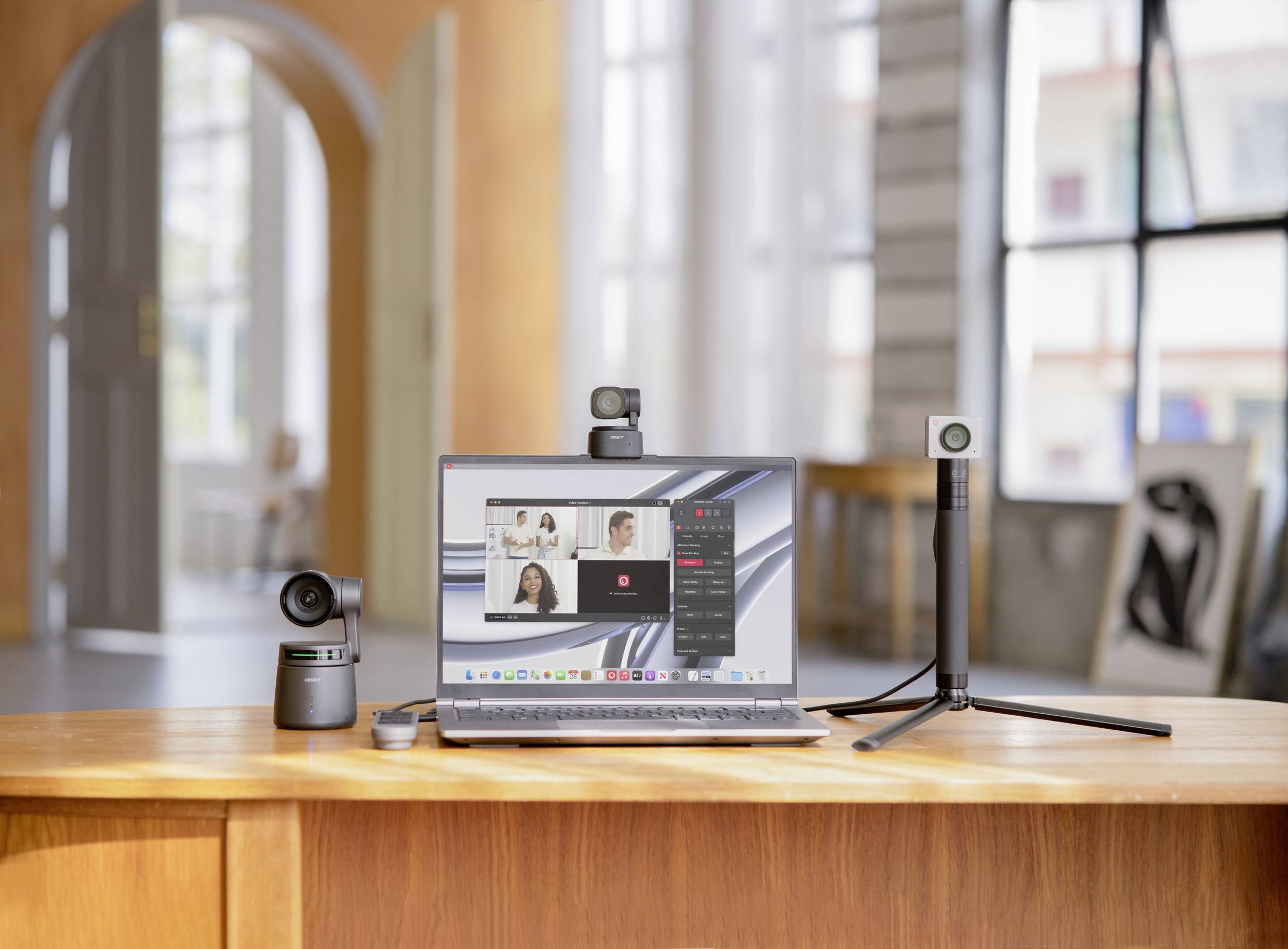 A laptop is sitting on a table in a well-lit room. A video conference with multiple people is displayed on the screen.