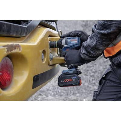 A person is using a Bosch cordless drill to tighten a screw on a yellow piece of construction machinery.