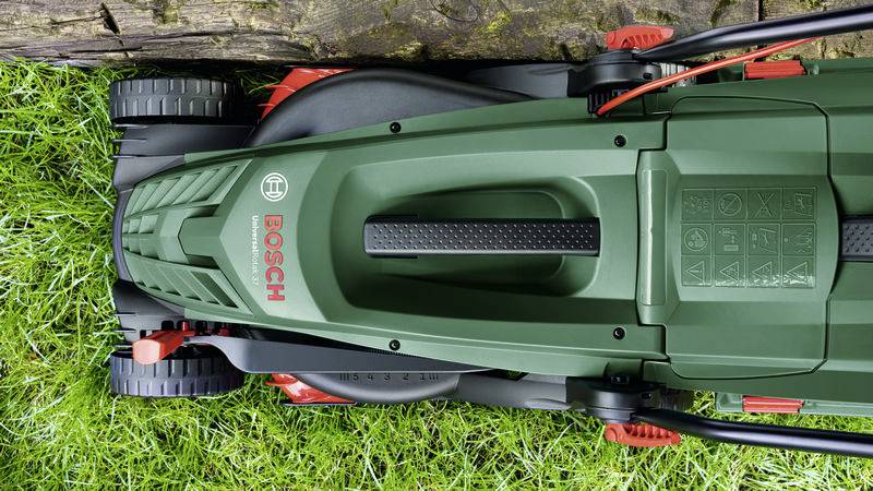 'Overhead view of a green lawnmower on grass, near a wooden plank. The Bosch brand name is visible.'