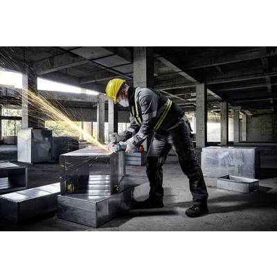 A person wearing a hard hat and mask is grinding metal in a partially completed building, with sparks flying during the work.