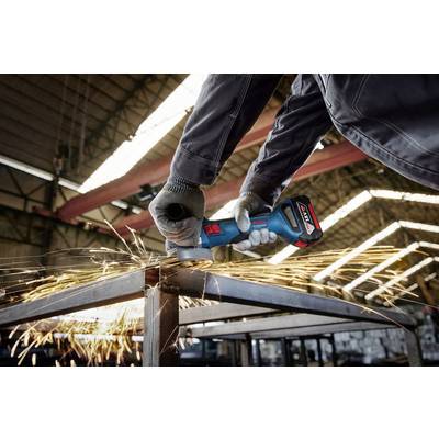 A person in workwear is using an angle grinder to cut metal. Sparks are flying away from the cutting point.